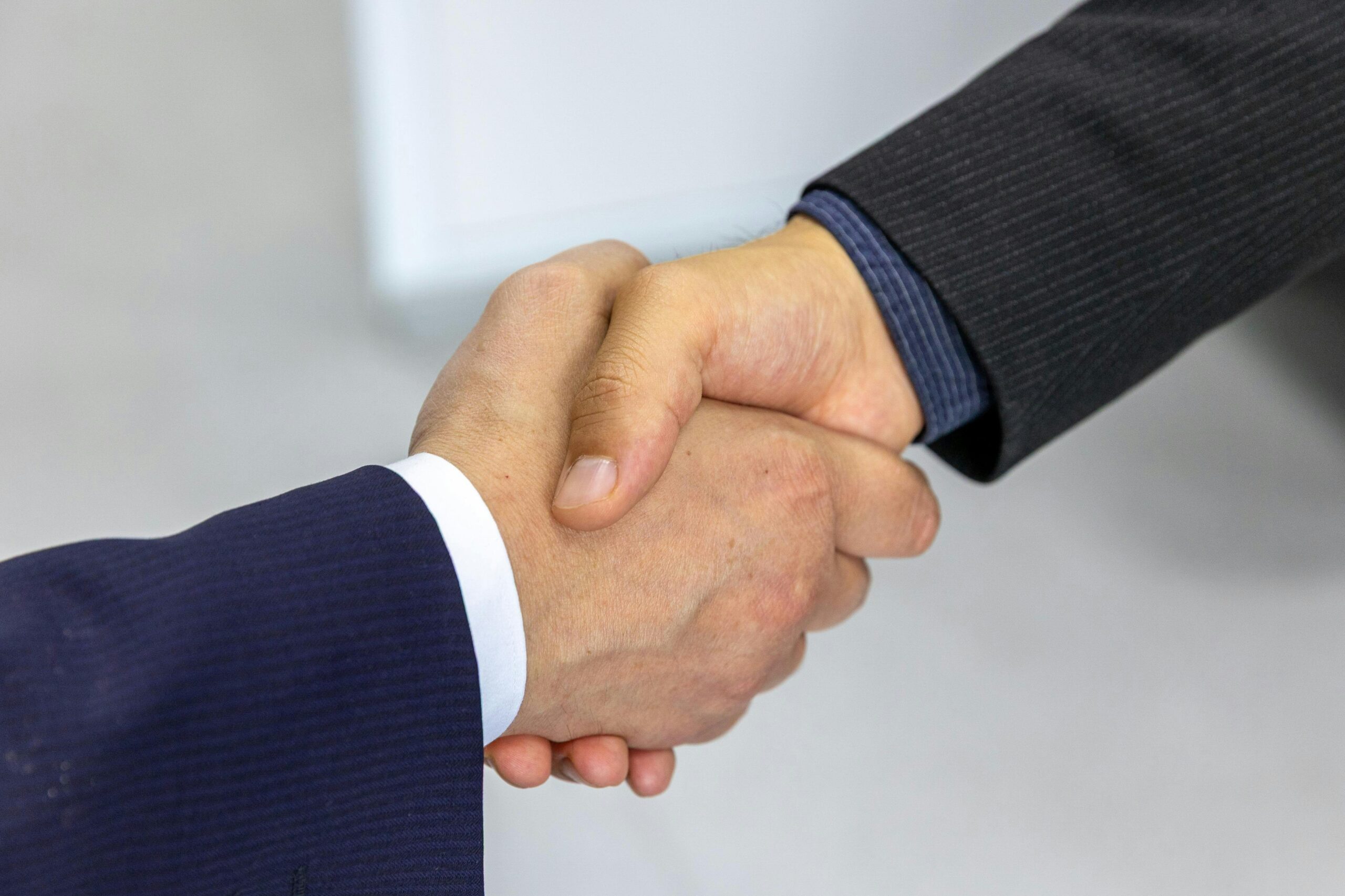 Quienes somos Close-up of two businessmen shaking hands, symbolizing agreement and partnership.